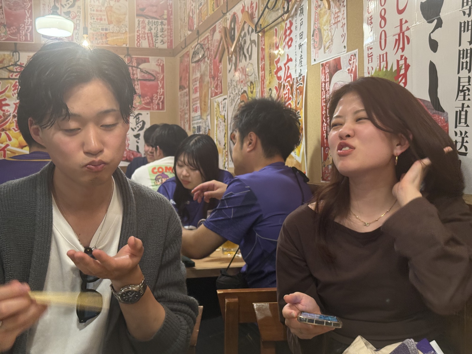 Young people dining together at a traditional Hiroshima izakaya.