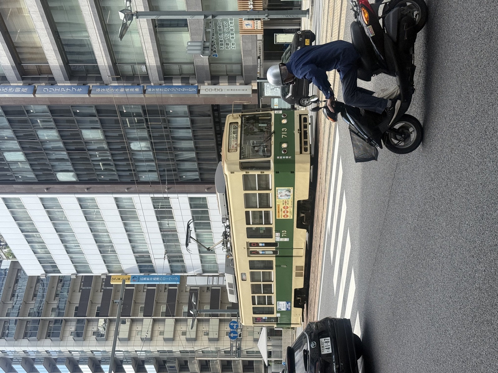 Vintage yellow-green Hiroden streetcar traveling through downtown Hiroshima