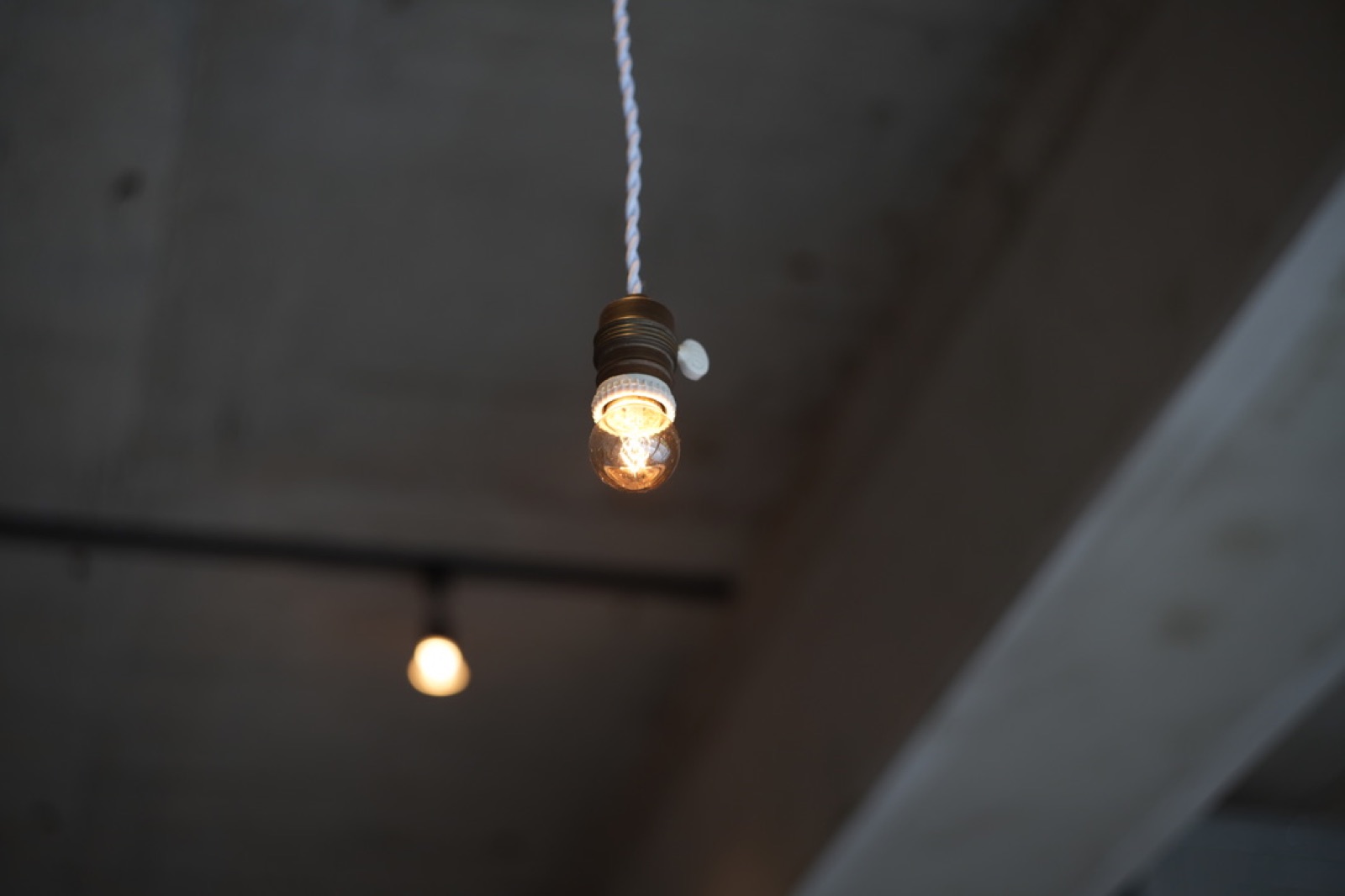 Pendant bulb glowing against a concrete ceiling in central Hiroshima