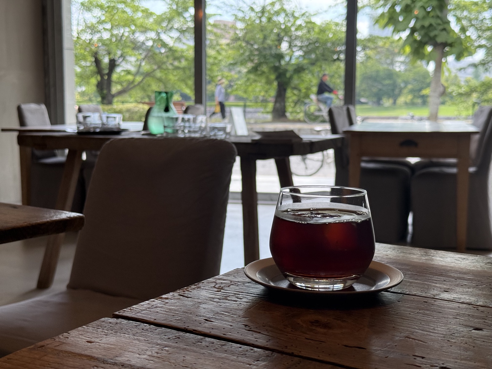 Cafe beverage with window view overlooking lush green Hiroshima park scenery