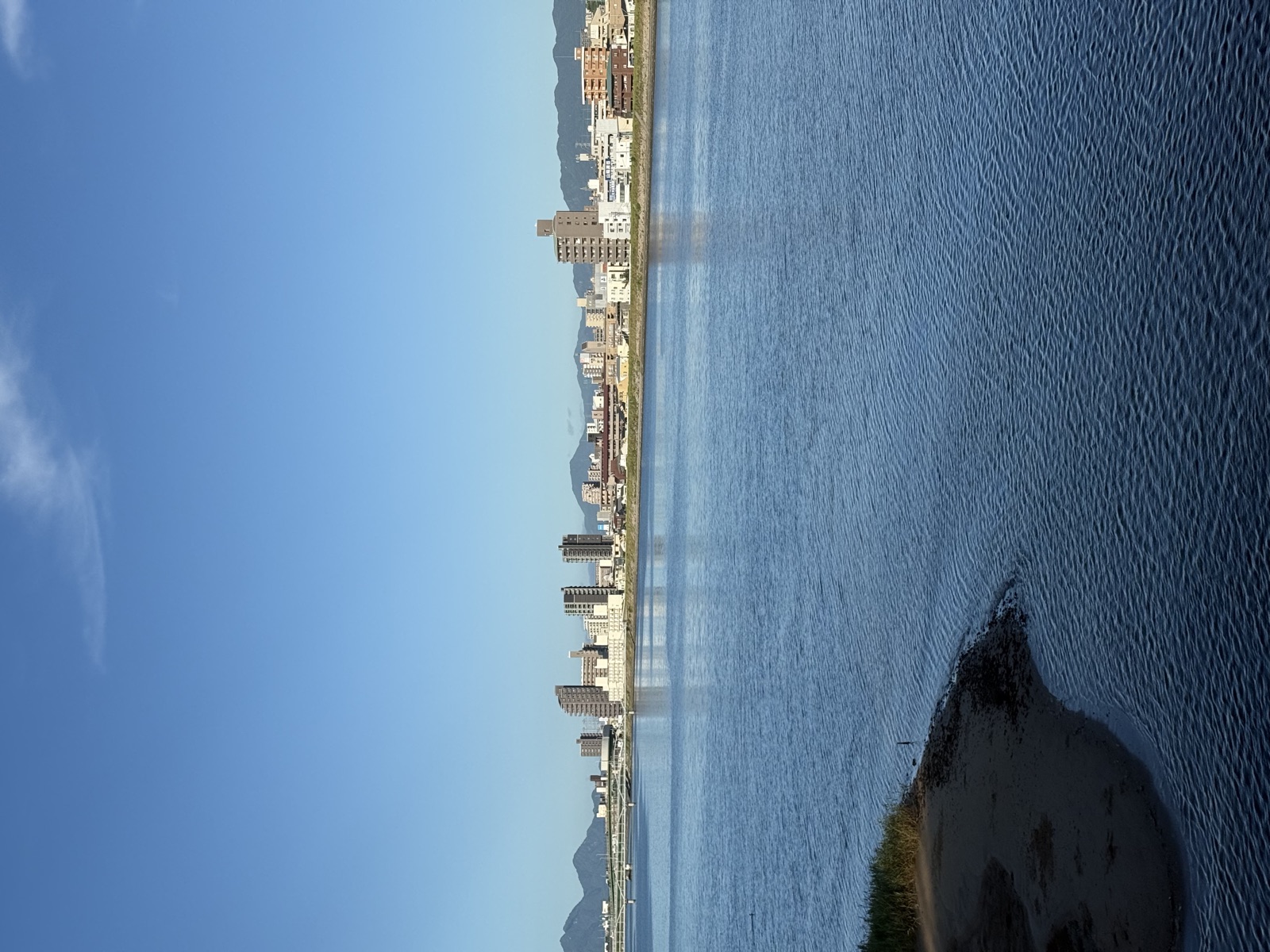 Hillside waterfront town overlooking strait with distant island view