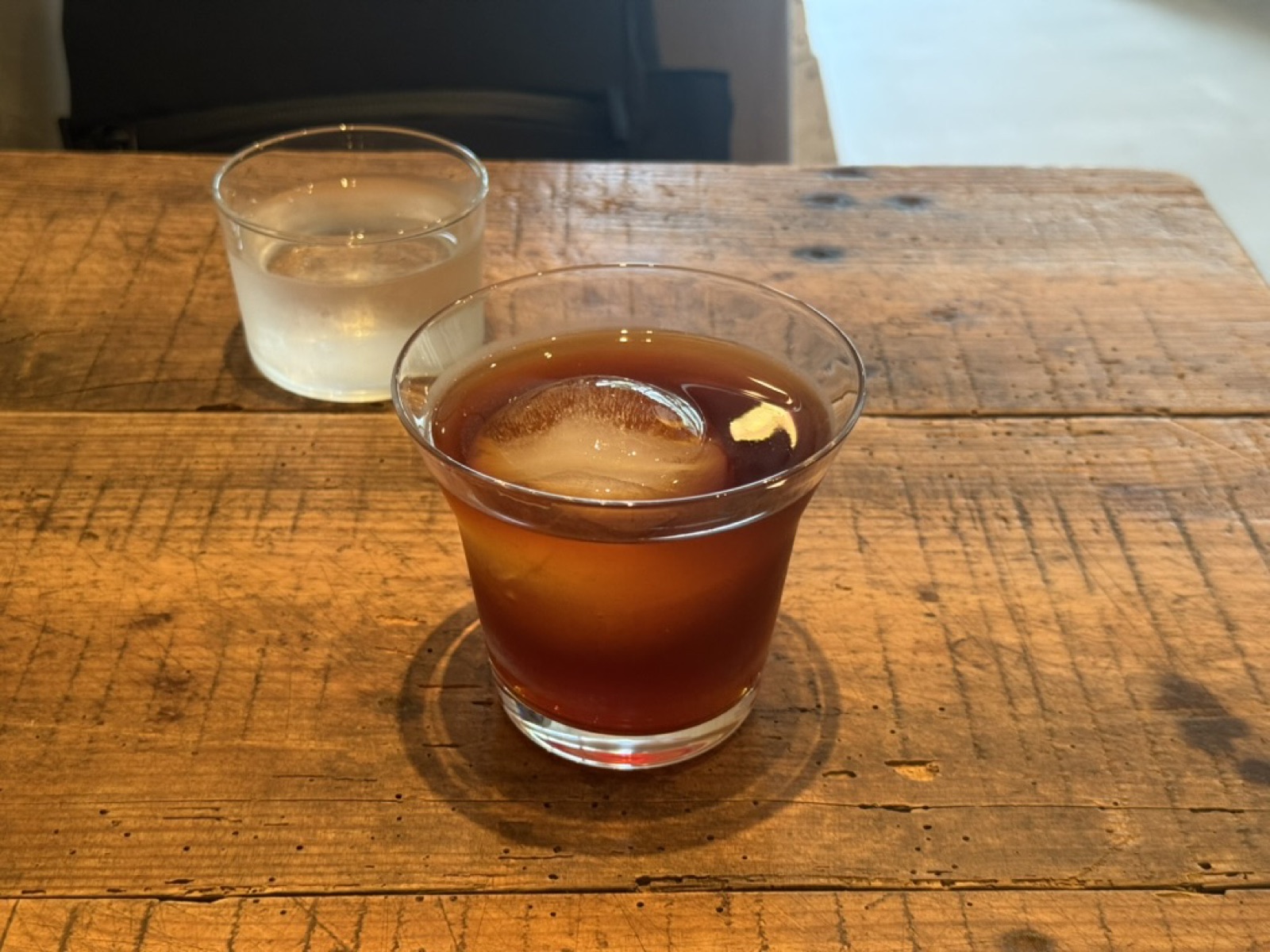 Iced cocktail with a chaser glass on a wooden counter