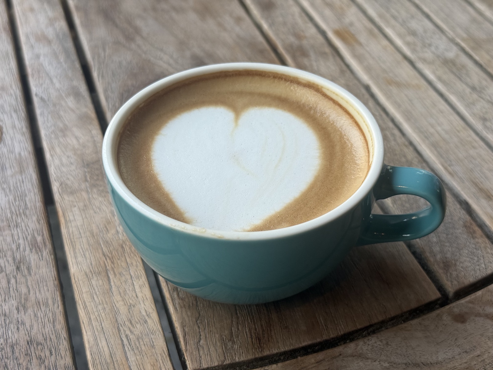 Coffee with latte art served on wooden table in cafe