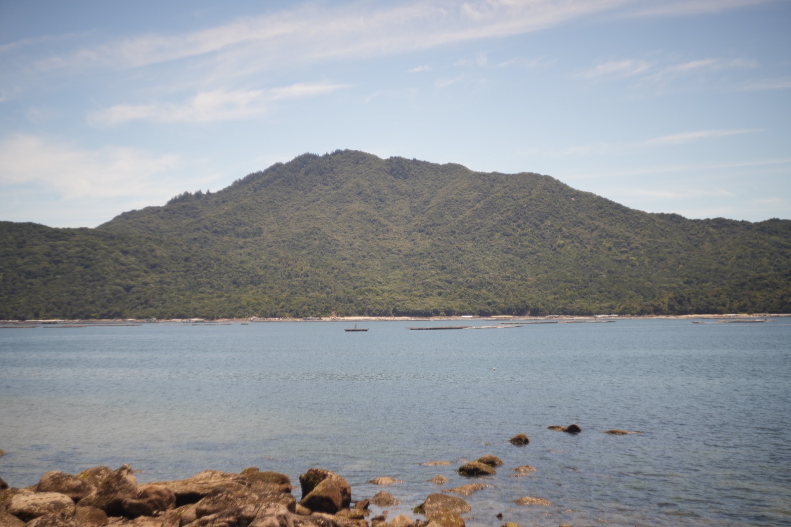 Lush green island viewed across calm blue Setonaikai waters from coastal shore