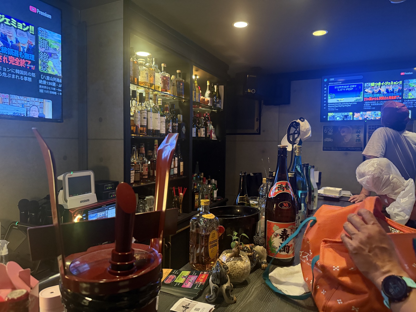 Traditional Japanese izakaya counter with spirit bottles and blue ambient bar lighting